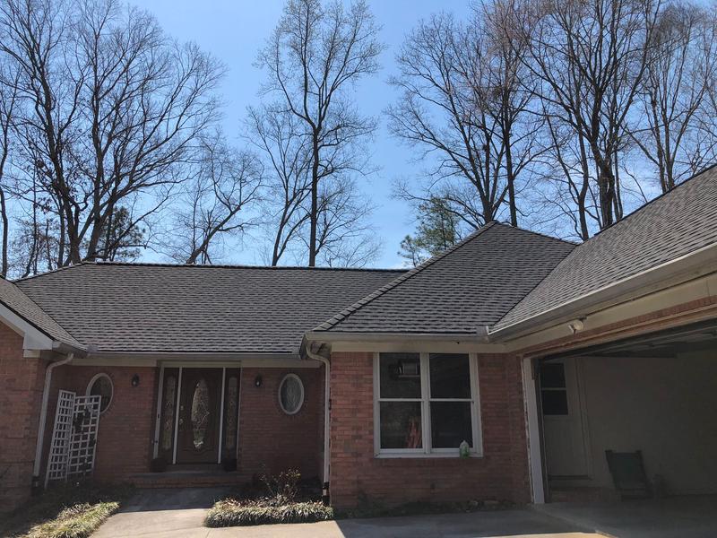 A brick home with a garage and trees in the background, showcasing a 3D roof animation design in New Jersey.